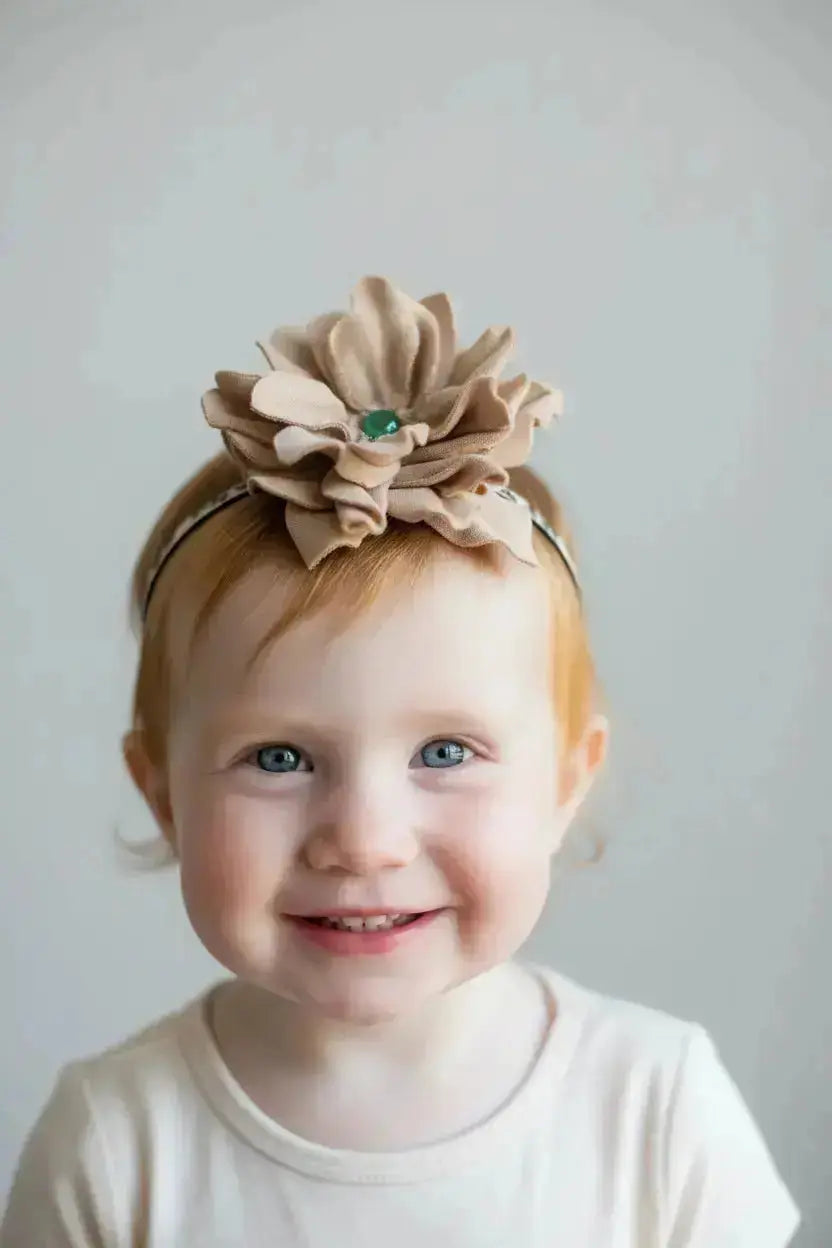 A little girl wearing a beautiful leather lace hair bow + headband w/ a green agate stone.