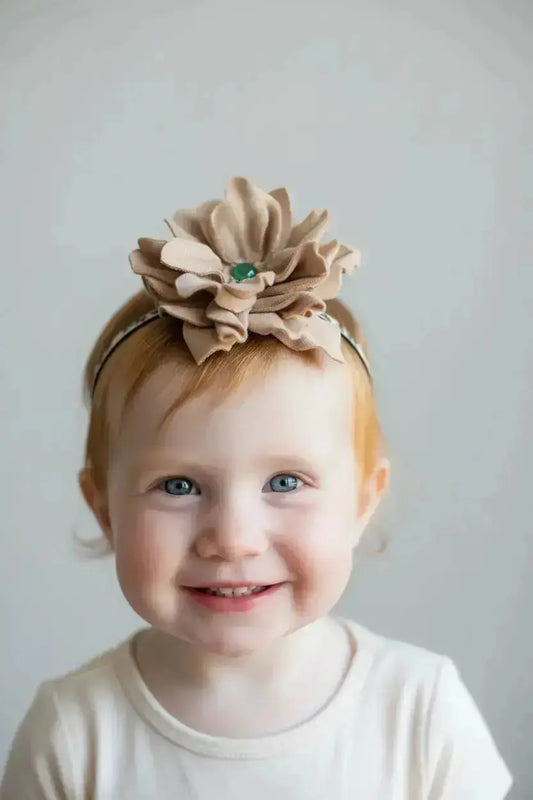 A little girl wearing a beautiful leather lace hair bow + headband w/ a green agate stone.