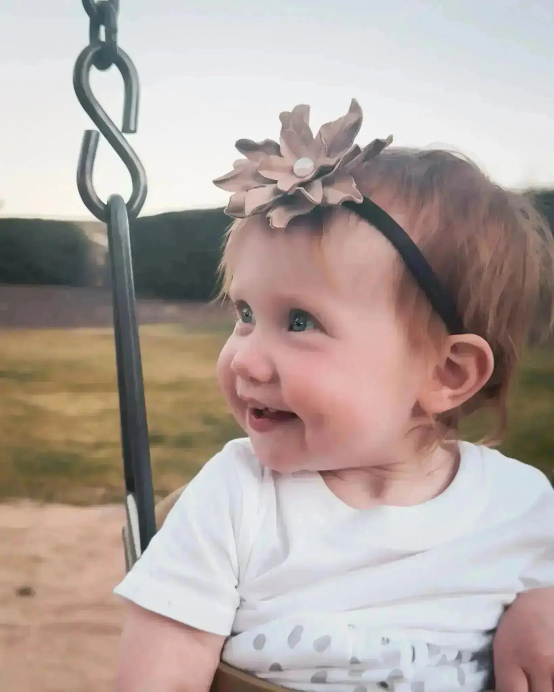 A little girl wearing a beautiful leather lace hair bow + headband w/ a pearl.