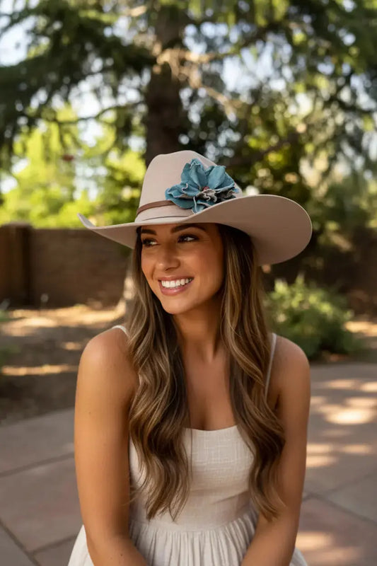 Woman wearing a felt cowgirl hat w/ a turquoise leather flower & red agate stone hat band. She is also wearing a cute dress outdoors.