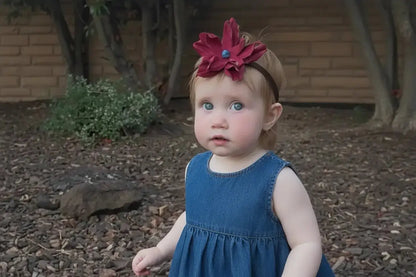 A little girl wearing a beautiful red leather lace hair bow + headband w/ a natural blue lapis stone.
