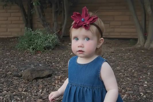 A little girl wearing a beautiful red leather lace hair bow + headband w/ a natural blue lapis stone.