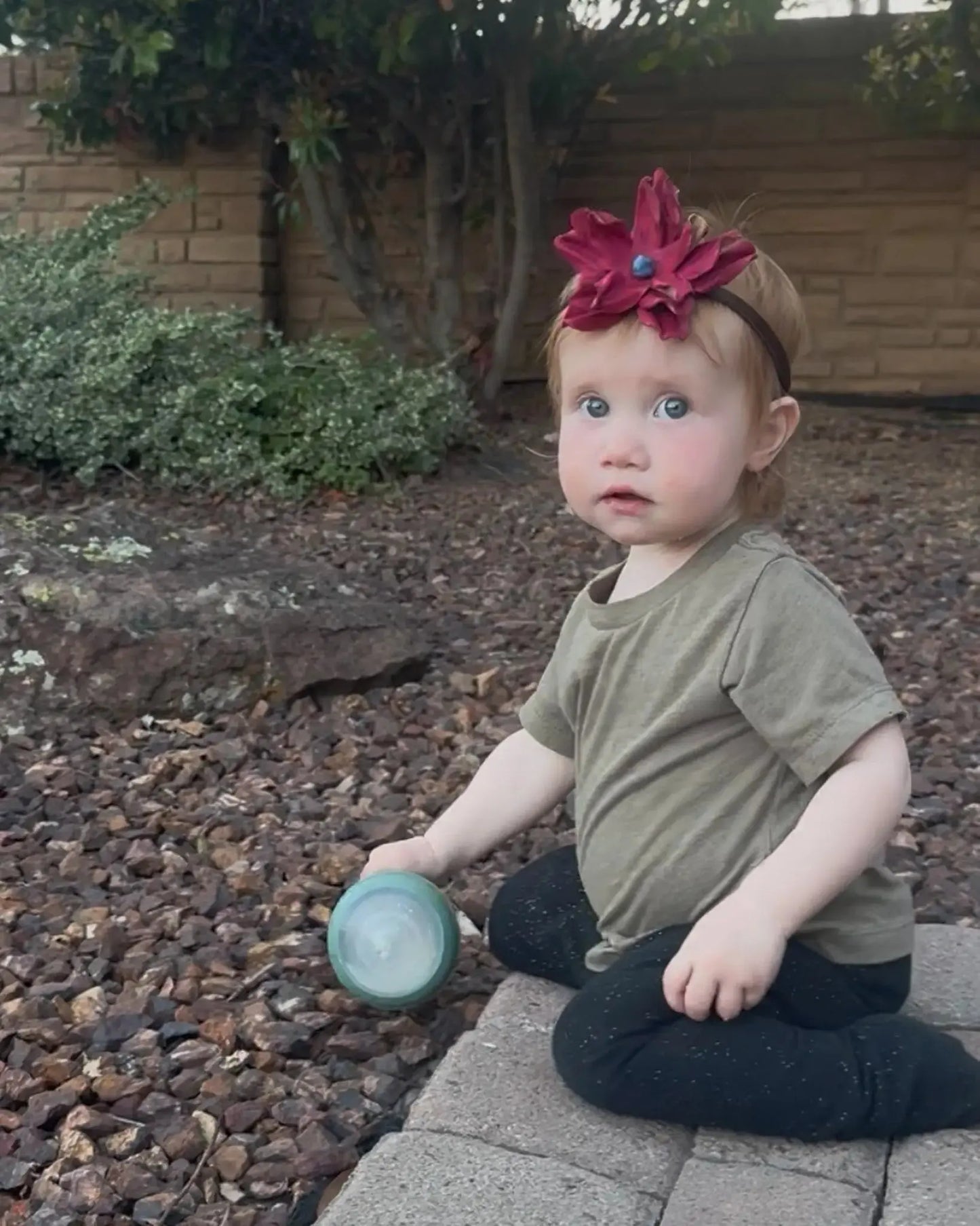 A little girl wearing a beautiful red leather lace hair bow + headband w/ a natural blue lapis stone.