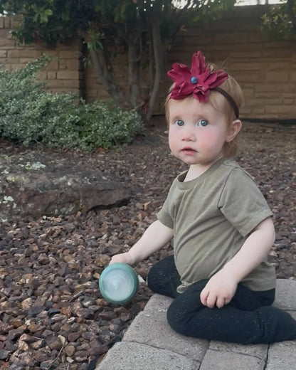 A little girl wearing a beautiful red leather lace hair bow + headband w/ a natural blue lapis stone.