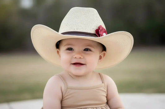 Baby girl wearing a cowgirl hat with a red leather flower and natural freshwater pearl hat band on it