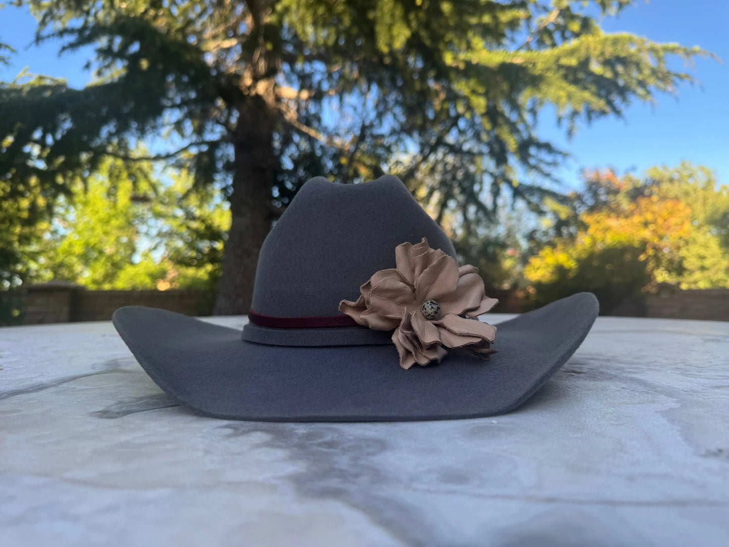 Cowgirl Hat w/ Leather Flower & Dalmatian Stone Hat Band Sitting on a Table w/ Nature in the Background.