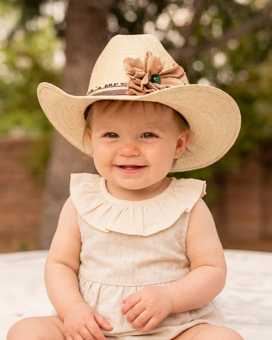 Baby girl wearing a cowgirl hat with a leather flower and leopard leather lace hat band on it.