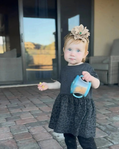 Little girl wearing a leather flower hair bow w/ a green agate stone in the center. It is worn as a headband. Westside Cowgirl.