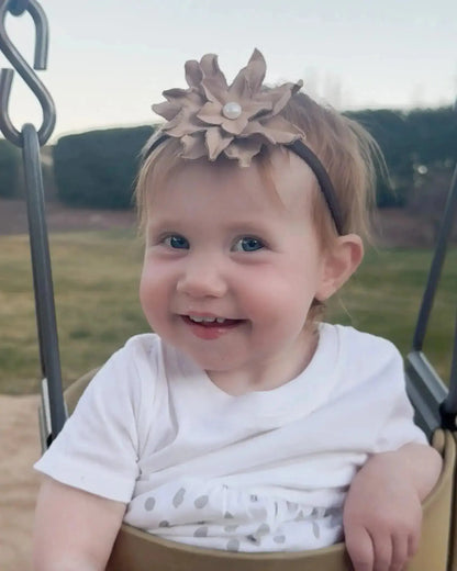 Little girl wearing a leather hair bow + headband w/ a natural freshwater pearl in the center. 