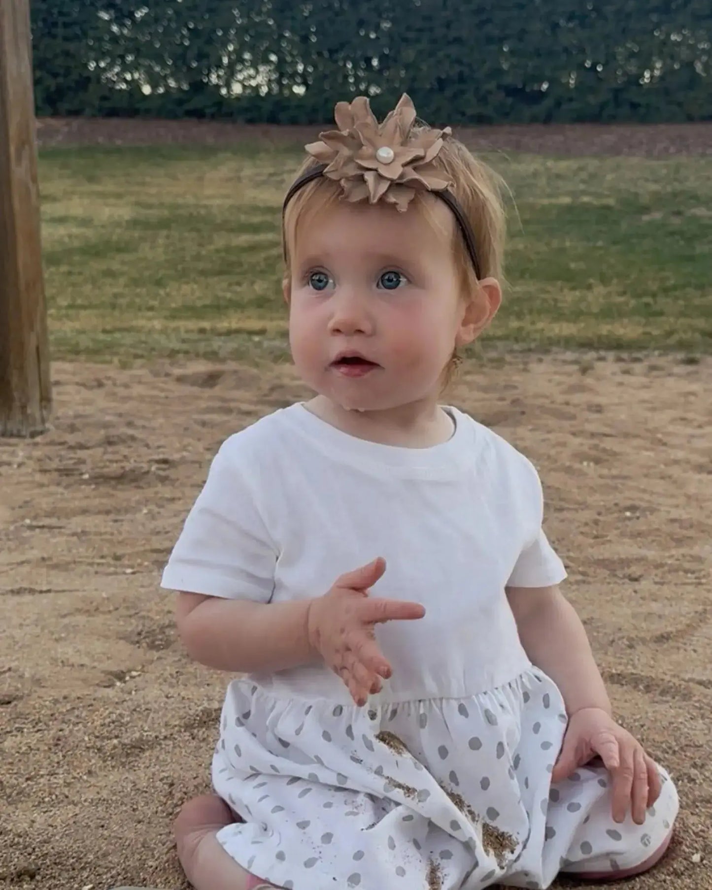 Little girl wearing a leather hair bow + headband w/ a natural freshwater pearl in the center. 