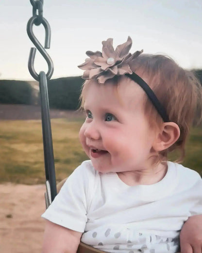 Little girl wearing a leather hair bow + headband w/ a natural freshwater pearl in the center. 