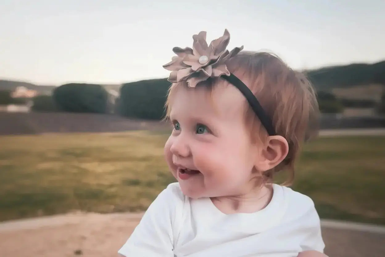 Little girl wearing a leather hair bow + headband w/ a natural freshwater pearl in the center. 